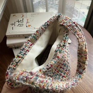 Close-up of woven tweed bag showing magnetic clasp and cream canvas lining detail