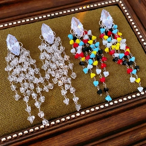 Detailed macro view of diamond-shaped crystal earrings with colorful tassel heart beads
