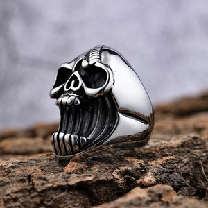 Macro side view of a vintage silver punk skull ring on tree bark with gothic details