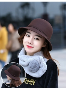 Dettaglio di cappello in lana marrone con fiocco e sciarpa grigia in ecopelliccia