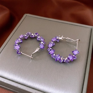 Silver hoop earrings with purple rhombic zircons shown on a premium jewelry gift box