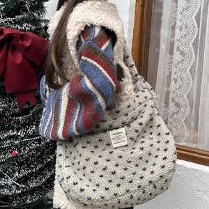 Detailed view of plush beige crossbody bag with blue patterns in a cozy winter setting
