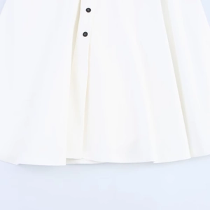 White V-neck dress detail showing high waist with double black buttons and smooth fabric