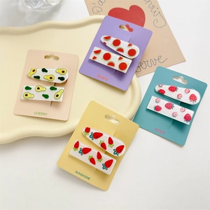 Detail of colorful fruit-themed hair clips with avocado, watermelon, and strawberry patterns