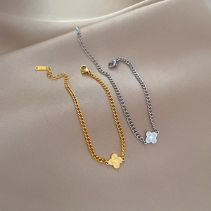 Minimalist clover chain bracelets in gold and silver finish on silk background