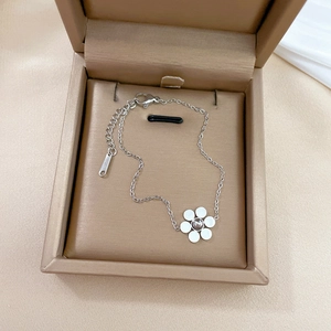 Detail of silver stainless steel chain bracelet featuring a white flower charm in a gift box