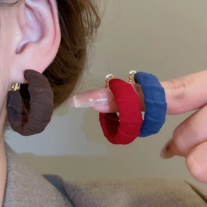 Detail of C-shaped fabric hoop earrings with velvet texture in red, blue and brown