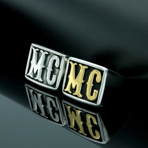 Close-up of gold and silver signet rings with MC engraving on a black mirror surface