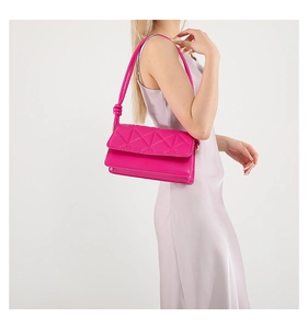 Detail of rose red shoulder bag with geometric quilted pattern and knotted strap