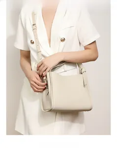 Close-up of creamy white lychee grain leather bucket bag with metallic buckle detail