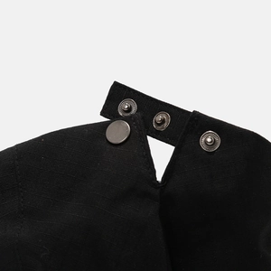 Macro shot of silver metal snap buttons on black twill fabric detailing the closure
