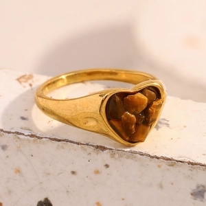 Detailansicht eines 18K vergoldeten Herzrings mit Tigeraugen-Inlay auf Steinuntergrund