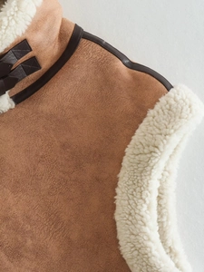 Detail of brown faux suede vest with soft white sherpa lining and leather neck buckle