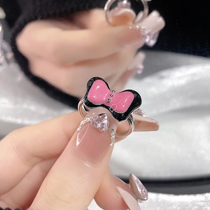 Close-up of pink and black bow ring with silver studs on hand for sizing