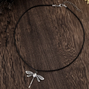 Λεπτομέρεια vintage μενταγιόν λιβελούλα με φεγγαρόπετρα σε σκούρα ξύλινη επιφάνεια