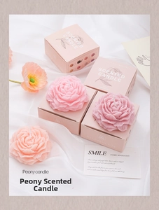Detail view of peony shaped scented candles in pink gift boxes with elegant silk background