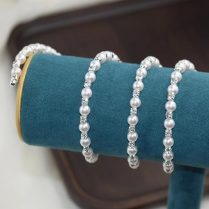 Detailed macro of 6mm white pearls and square rhinestones on a silver bangle bracelet