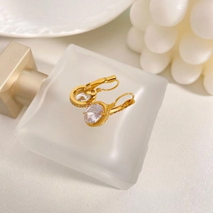 Macro detail of vintage gold-plated oval zircon earrings with intricate carved patterns