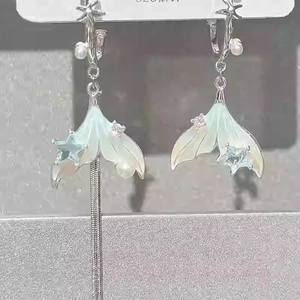 Detail of silver asymmetric fishtail earrings with pearls and long metal tassels