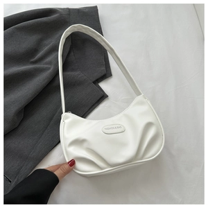 Detail showing white pleated faux leather texture and fashion brand tag on the crescent bag