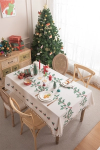 Close-up of Christmas tablecloth with holly berry patterns and beige tassel fringe details