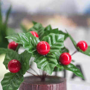 Artificial red berry plant with green leaves in a dark brown wood grain base