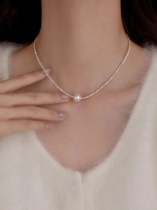 Close-up of white pearl pendant on silver beaded chain necklace worn on neck