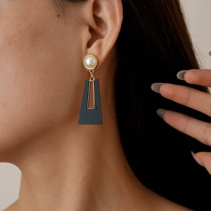Detail of vintage acrylic faux pearl drop earrings on model showcasing geometric hollow design