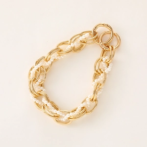 Close-up of golden multi-layer metal chain interwoven with white pearls and lobster clasp