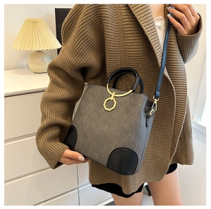 Detail view of large grey bucket bag with monogram print and golden metal hardware