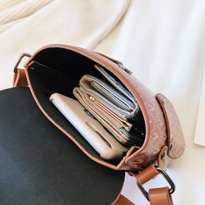 Top view of the interior capacity of a brown printed small crossbody bag with a phone