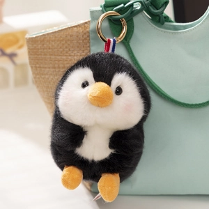 Cute plush penguin pendant keychain with ribbon detail on a light green backpack