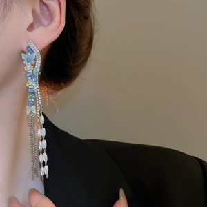 Macro detail of butterfly tassel earrings with blue gradient crystals and white pearls