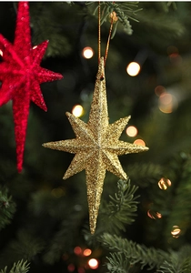 Close-up of golden and red glittering star ornaments hanging on a Christmas tree