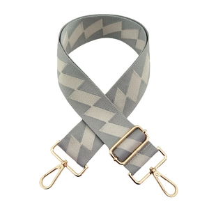 Detail of grey and beige zigzag pattern bag strap with adjustable gold buckle