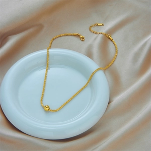 Golden twisted rope chain necklace with polished sphere pendant on elegant silk display