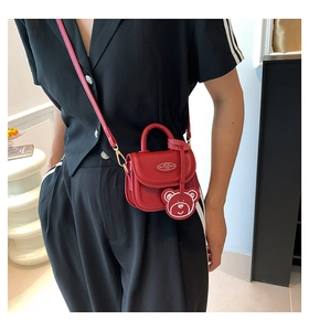 Detail of red mini crossbody bag with cute bear charm and adjustable shoulder strap