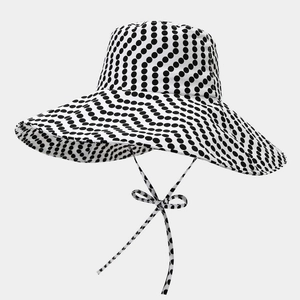 Dettaglio del cappello da sole a pois a tesa larga con fiocco decorativo antivento