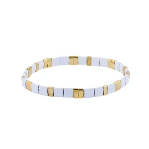Macro detail of elastic stretch bracelet featuring alternating gold and white enamel tiles