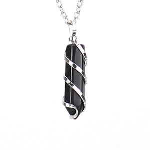 Detail of a black obsidian hexagonal point pendant wrapped in silver spiral wire