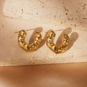 Gold hollow heart earrings with hammered lava texture on stone and silk background