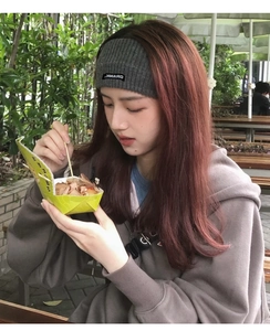 Close-up of a wide dark grey ribbed knit headband worn by a model in casual outdoor setting