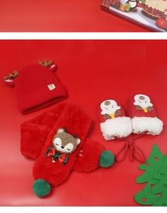 Flat lay of red knit Christmas baby hat, plush scarf, and gloves with reindeer antlers
