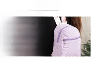 Detail of a purple and white striped seersucker backpack showing smooth metal zipper