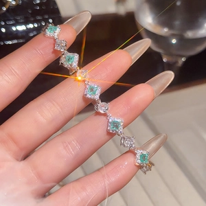Macro detail of luxury silver bracelet featuring green crystals and sparkling zircons