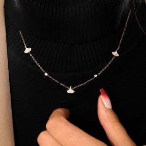 Detail of a gold necklace with sparkling ginkgo leaf pendants on a black sweater