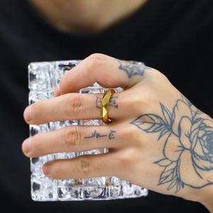 Close-up of golden geometric faceted titanium steel ring worn on hand holding glass