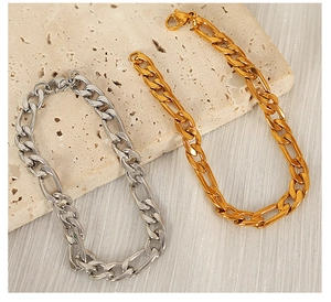 Detailed close-up of gold and silver Figaro chain bracelets on a textured stone surface