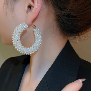Close-up of gold-plated large hoop earring with white pearls and sparkling crystals