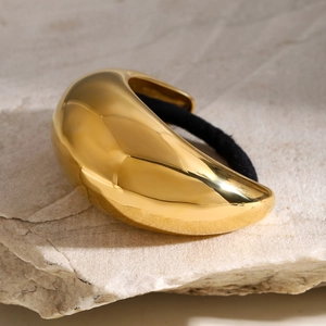 Macro shot of gold metallic hair tie buckle on a stone base with black elastic band